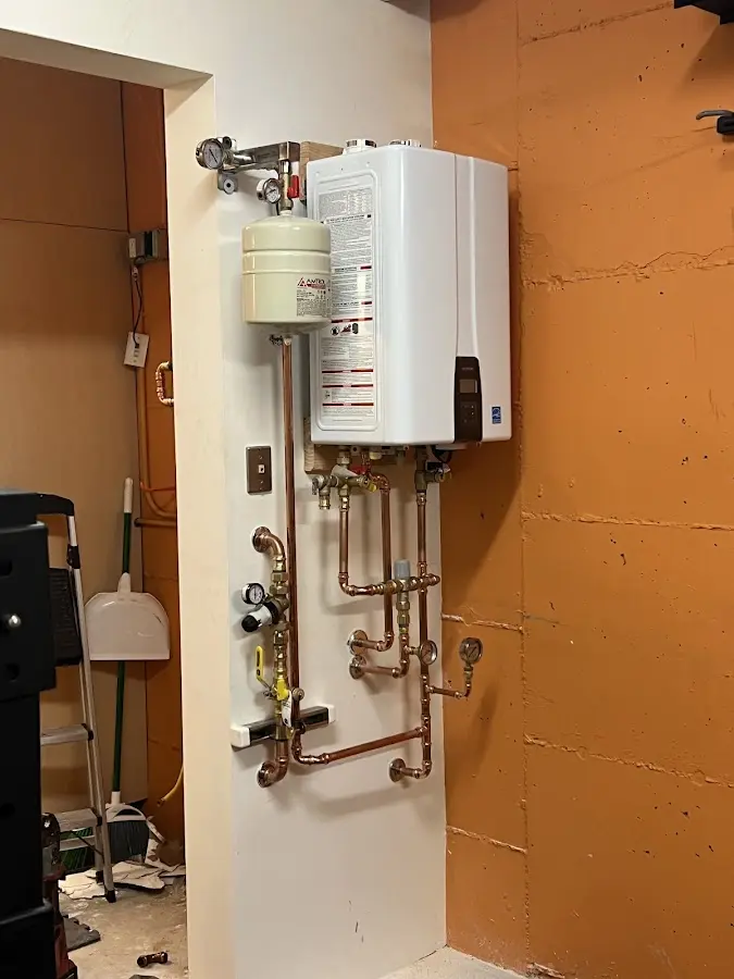 Plumbing technician inspecting water heater connections in Winchester